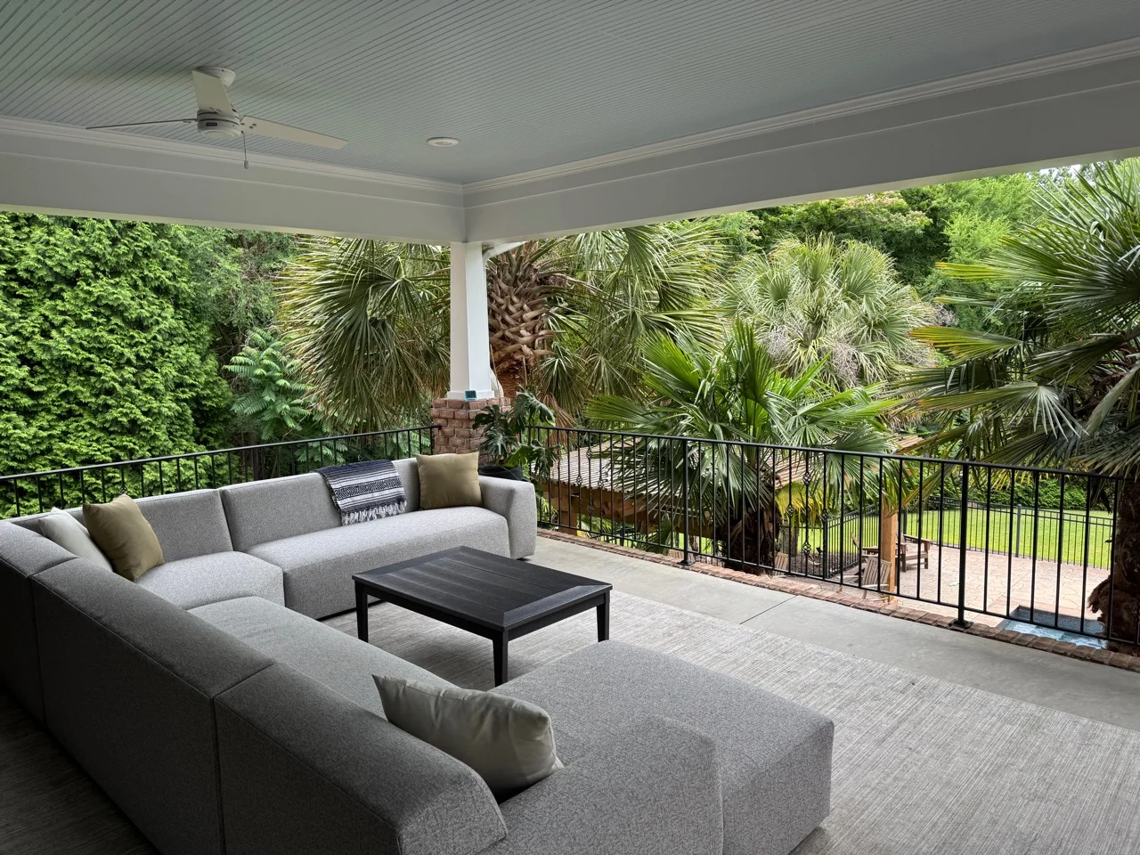 Covered porch with a sectional sofa, ceiling fan, and garden outlook